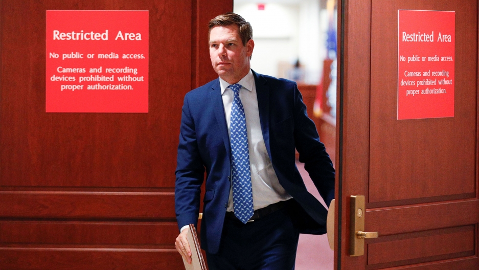 Representative Eric Swalwell exits the House of Representatives Sensitive Compartmented Information Facility during a break in the impeachment inquiry, Nov. 7, 2019. Representative Eric Swalwell is shown wearing a blue suit and exiting a room with red signs saying "Restricted Area."