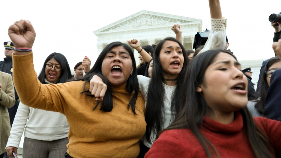 DACA plaintiffs walk arm-in-arm down from the US Supreme Court after justices heard oral arguments in cases before the court regarding the Trump administration's bid to end the Deferred Action for Childhood Arrivals (DACA) program in Washington, DC, Nov. A group of people are shown shouting and with their hands in the air outside of the US Supreme Court.