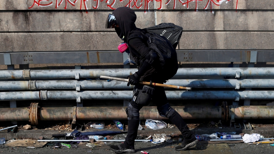 A protester walks at the occupied campus of the Chinese University in Hong Kong, China, Nov. 13, 2019. A person is shown in all black with their hood up over their head as they are walking with a metal poll.