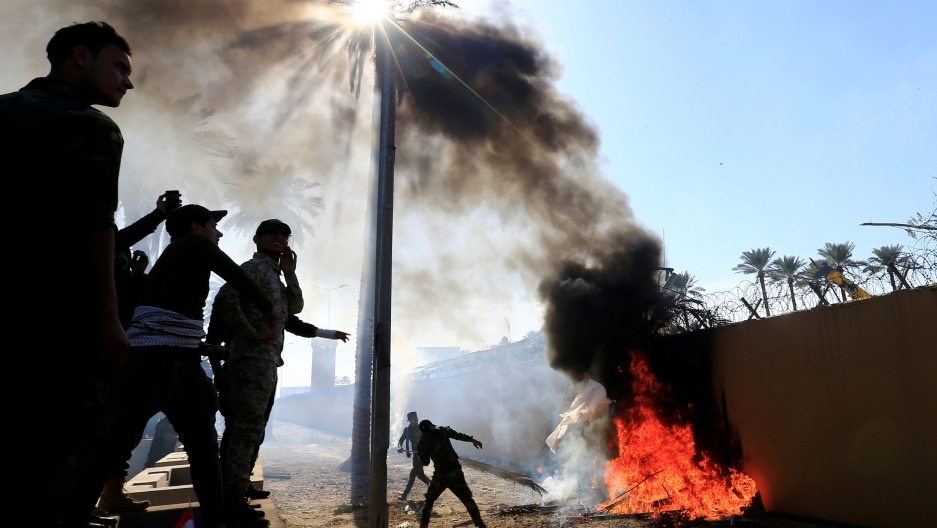 Hashd al-Shaabi paramilitary fighters set fire on the US Embassy wall to condemn air strikes on their bases, in Baghdad, Iraq Dec. 31, 2019. The US Embassy wall is shown set on fire by a group of people adjacent.