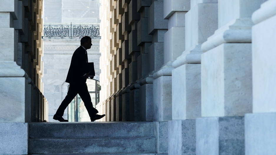 Chief Justice of the United States John Roberts arrives to preside over the Senate impeachment trial of President Donald Trump in Washington, DC, Jan. 21, 2020. Chief Justice of the United States John Roberts is shown in shadow holding a folder and framed by the stone walls fo the Capitol building.