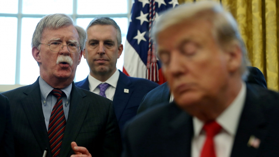 US President Donald Trump listens as his then national security adviser John Bolton speaks during a presidential memorandum signing at the White House in Washington, DC, Feb. 7, 2019. US President Donald Trump is shown in soft focus in the near ground as John Bolton speaks from behind him.