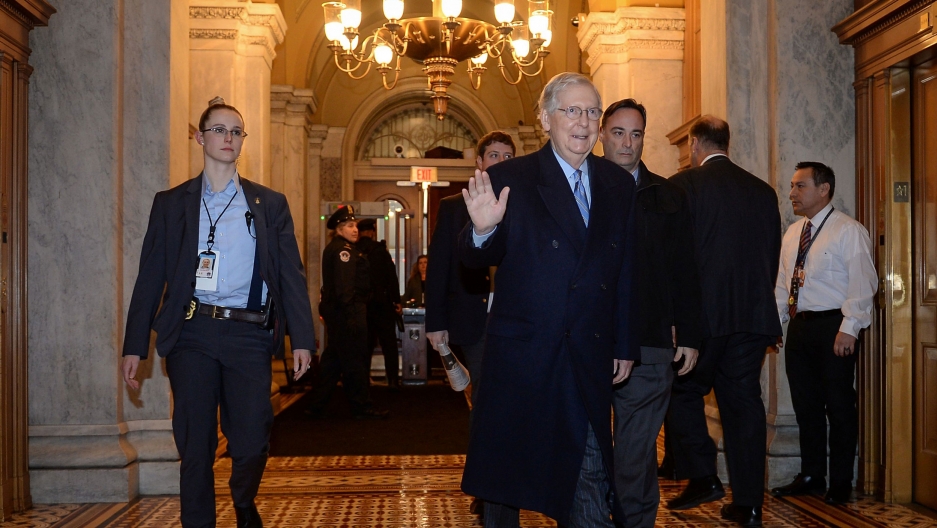 Senate Majority Leader Mitch McConnell arrives at the US Capitol before the start of Friday's Senate impeachment trial of President Donald Trump in Washington, DC, Jan. 31, 2020. Senate Majority Leader Mitch McConnell is shown walking with security personel and weaing a dark overcoat.