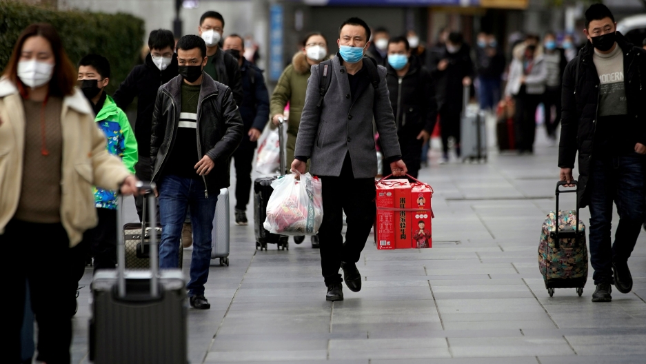 Passengers wearing masks walk outside the Shanghai railway station in Shanghai, China, as the country is hit by an outbreak of a coronavirus, Feb. 2, 2020. Train passengers are shown walking and wearing face masks.
