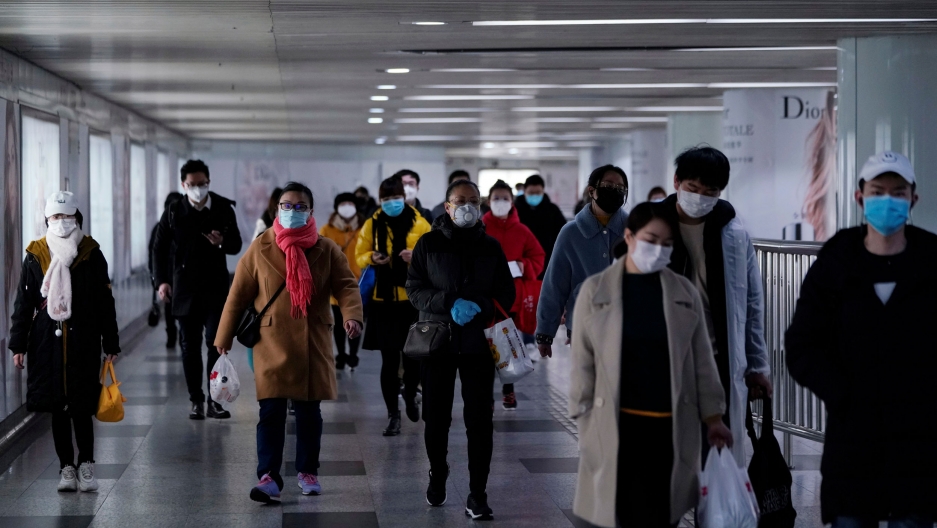 People wearing face masks are seen in an underpass leading to a subway station in the morning after the extended Lunar New Year holiday caused by the novel coronavirus outbreak, in Shanghai, China, Feb. 10, 2020. A group of people are shown walking and wearing face masks.