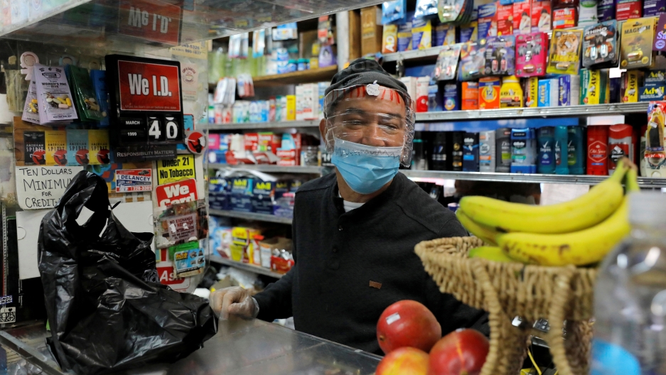 Bodega manager Rafael Perez wears a homemade face protector, fashioned from a water bottle, as he works in the Chinese Hispanic Grocery during the coronavirus disease (COVID-19) outbreak in New York City, New York, April 2, 2020. Bodega manager Rafael Perez wears a homemade face protector, fashioned from a water bottle, as he works in the Chinese Hispanic Grocery during the coronavirus disease (COVID-19) outbreak in New York City, New York, April 2, 2020.