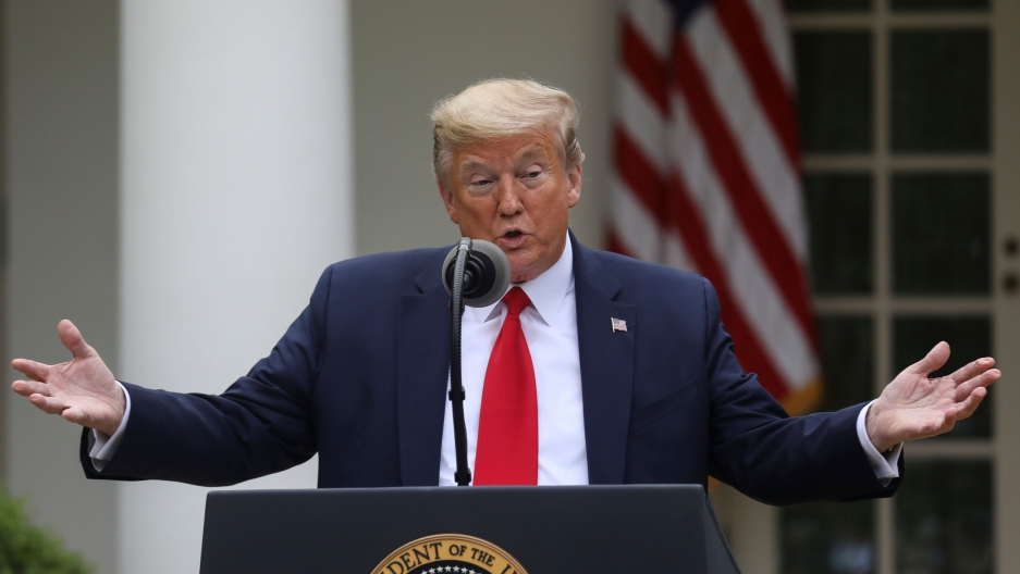 US President Donald Trump addresses the daily coronavirus task force briefing at the White House, April 14, 2020. US President Donald Trump is shown standing at a podium with both of his arms outstretched.