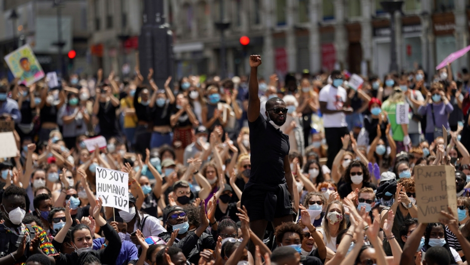 A man raises his fist over a crowd of demonstrators during a protest against racial inequality in the aftermath of the death in Minneapolis police custody of George Floyd, at Puerta del Sol square in Madrid, Spain, June 7, 2020. A large group of people are shown in a crowd with man in the middle raising his right fist in the air.