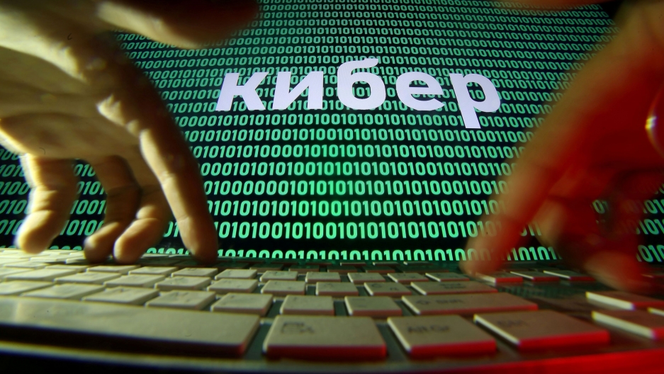 Hands are seen on a keyboard in front of a displayed code in this picture illustration. A screen is shown with green zeros and ones with a white keyboard in the nearground.