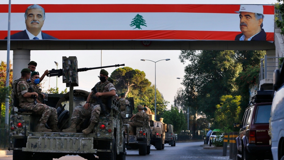 A Lebanese army convoy pass under a Lebanese flags with pictures of slain Lebanese Prime Minister Rafik Hariri in Beirut, Lebanon, Tuesday, Aug. 18, 2020. A convoy of military vehicles, some equipped with weapons, pass under a large Lebanese flag with pictures of slain Lebanese Prime Minister Rafik Hariri.