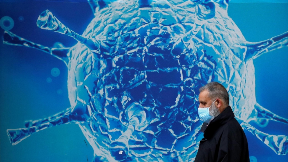A man wearing a protective face mask walks past an illustration of a virus outside a regional science centre amid the coronavirus disease (COVID-19) outbreak, in Oldham, Britain, August 3, 2020. A man wearing a protective face mask walks past an illustration of a virus outside a regional science centre amid the coronavirus disease (COVID-19) outbreak, in Oldham, Britain, August 3, 2020.