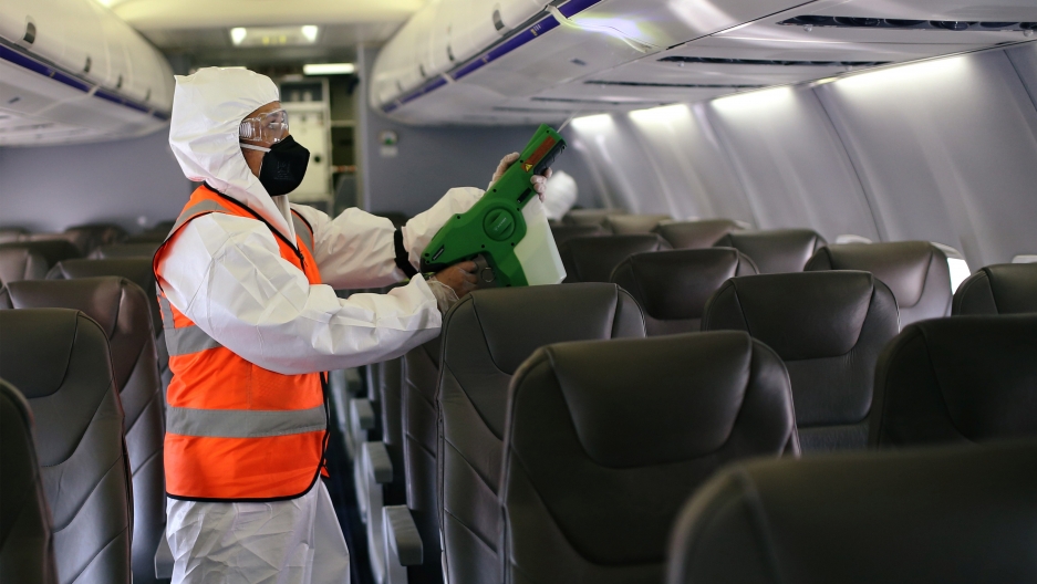 A man wearing protective gear disinfects inside an airplane at the El Dorado International Airport amid the coronavirus pandemic, in Bogota, Colombia, Aug. 31, 2020. A person wearing a hazmat suit appears cleaning inside an airplane.