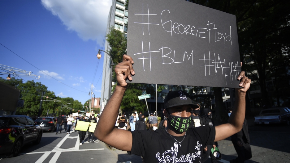 A demonstrator holding a sign reading #GeorgeFloyd and #BLM marches near Ebenezer Baptist Church in Atlanta, Georgia, May 30, 2020. 
