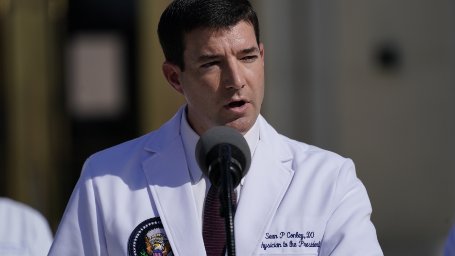 Dr. Sean Conley, physician to US President Donald Trump, talks with reporters at Walter Reed National Military Medical Center, Oct. 5, 2020, in Bethesda, Md. Dr. Sean Conley, physician to US President Donald Trump, is shown wearing a white medical jacket with a US presidential shield page on the breast.