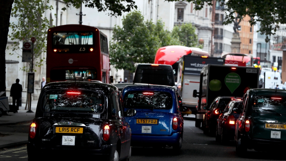 Vehicles drive on a congested London street, 2017. Several vehicles are shown bumper to bumper congested street.