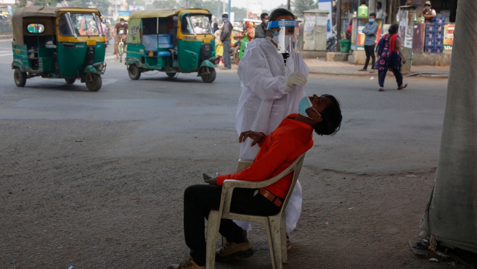 A health worker takes a nasal swab sample of a man to test for COVID-19 in Ahmedabad, India, Jan. 4, 2021. India on Sunday authorized two COVID-19 vaccines, paving the way for a huge inoculation program. A man is shown sitting with his head back and a medical professional taking a nasal swab from his nose.