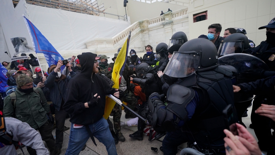 Trump supporters are shown breaking through a police barrier at the Capitol in Washington, Jan. 6, 2021. A large crowd of people are shown forcing their way past armed security officers at the US Capitol building.