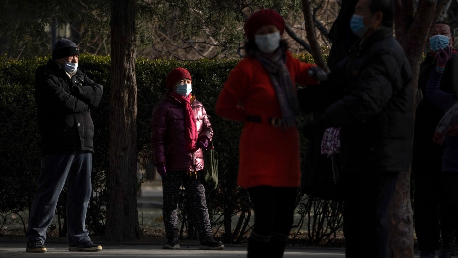 People wearing face masks to help curb the spread of the coronavirus at a public park in Beijing, Jan. 12, 2021. Several people are shown standing in a park and wearing face masks and winter jackes=ts.