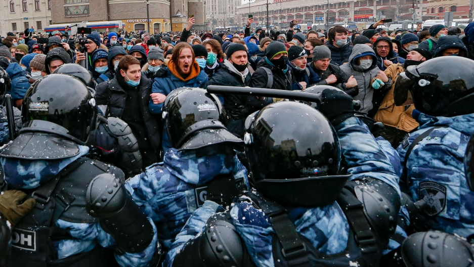 People clash with police during a protest against the jailing of opposition leader Alexei Navalny in Moscow, Russia, Jan. 31, 2021. A large crowd of people are shown lined up in opposition to a group of people armed in riot great.