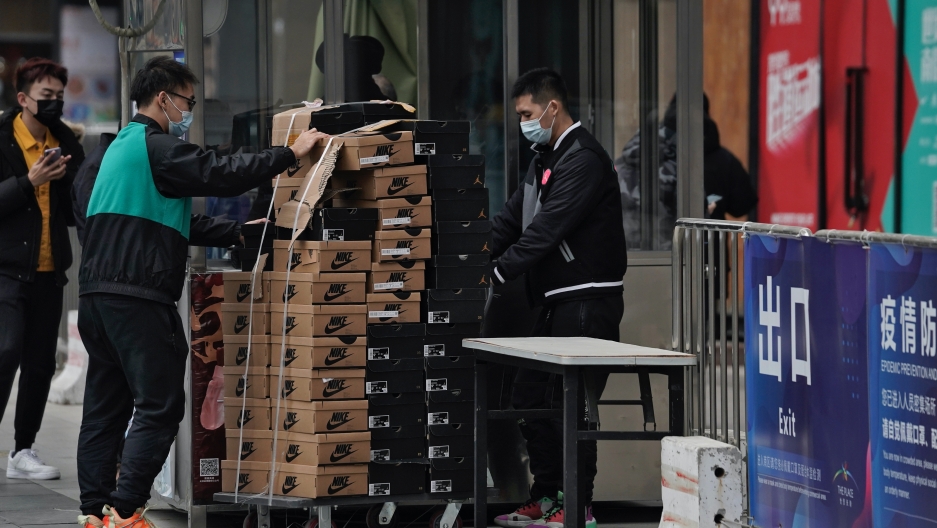 Workers wearing face masks to help curb the spread of the coronavirus push a cart loaded with shoes made by Nike past a security post at a shopping mall in Beijing, Jan. 14, 2021. China's exports rose in 2020 despite pressure from the coronavirus pandemic Workers wearing face masks to help curb the spread of the coronavirus push a cart loaded with shoes made by Nike past a security post at a shopping mall in Beijing, Jan. 14, 2021. China's exports rose in 2020 despite pressure from the coronavirus pandemic