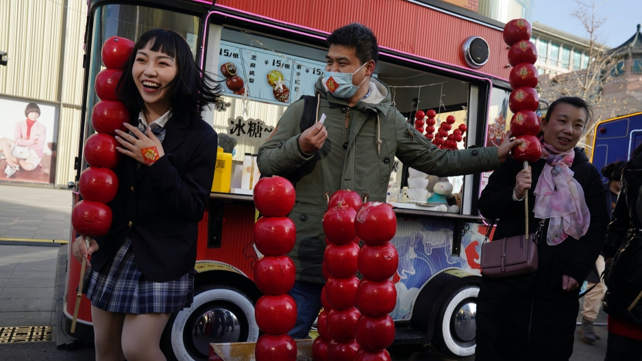 A Chinese woman reacts as she holds a giant replica of candy haw, a popular Beijing snack, at a street stall near Wangfujing on the fourth day of the Lunar Chinese New Year in Beijing on Feb. 15, 2021. A Chinese woman reacts as she holds a giant replica of candy haw, a popular Beijing snack, at a street stall near Wangfujing on the fourth day of the Lunar Chinese New Year in Beijing on Feb. 15, 2021.