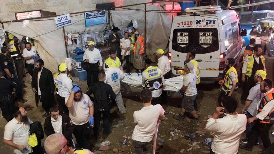 Israeli security officials and rescuers on the scene following a stampede during a Lag Ba'Omer celebrations at Mt. Meron in northern Israel, April 30, 2021. A group of emergency medical professionals are shown with a ambulance in the background.