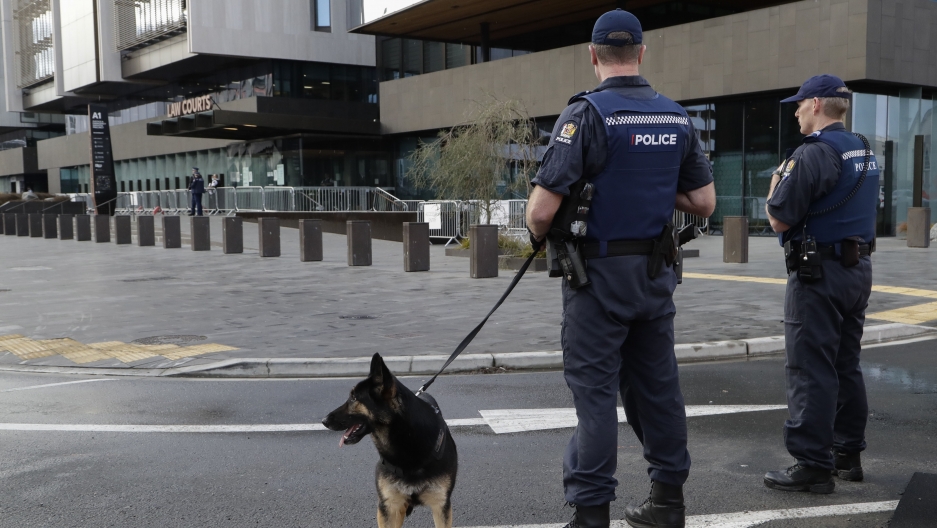 Police keep watch outside the Christchurch High Court ahead of day two of the sentencing hearing of Australian Brenton Harrison Tarrant, in Christchurch, New Zealand. Armed police stand in front of a building with a police dog