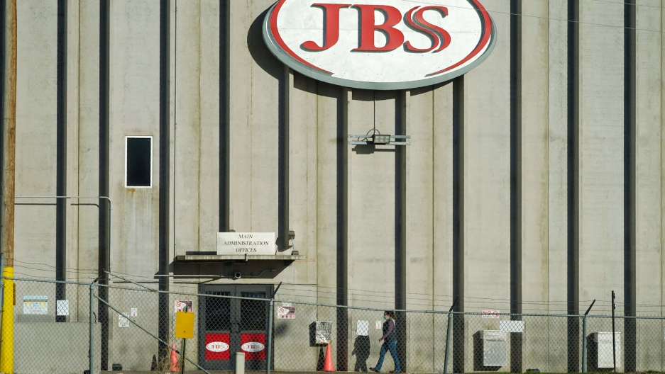 In this Oct. 12, 2020 file photo, a worker heads into the JBS meatpacking plant in Greeley, Colorado. JBS red sign on meat factory building facade.
