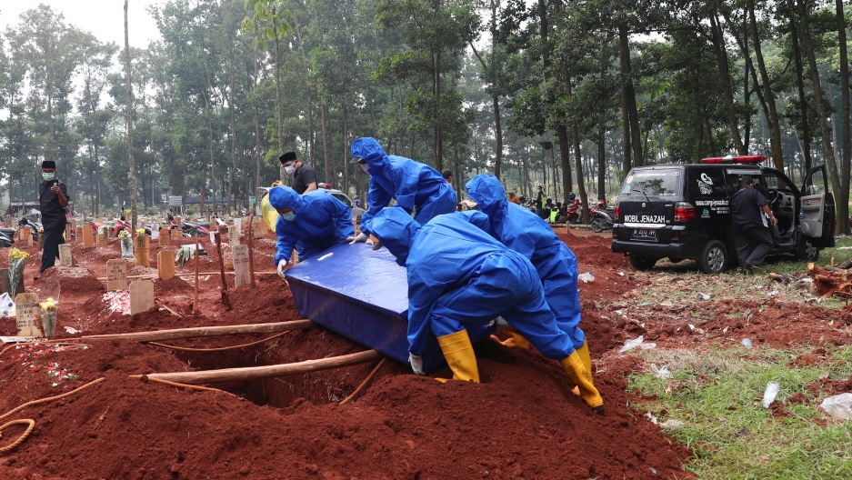 Workers in protective suits carry a coffin containing the body of a COVID-19 victim to a grave for a burial at Cipenjo cemetery in Bogor, West Java, Indonesia, Wednesday, July 14, 2021. Workers in protective suits carry a coffin containing the body of a COVID-19 victim to a grave for a burial at Cipenjo cemetery in Bogor, West Java, Indonesia, Wednesday, July 14, 2021.