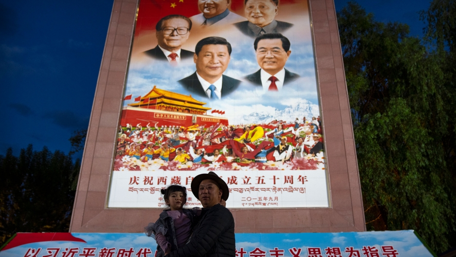 A man holds a girl as they pose for a photo in front of a large mural depicting Chinese President Xi Jinping, bottom center, and other Chinese leaders at a public square at the base of the Potala Palace in Lhasa in western China's Tibet Autonomous Region A man holds a girl as they pose for a photo in front of a large mural depicting Chinese President Xi Jinping, bottom center, and other Chinese leaders at a public square at the base of the Potala Palace in Lhasa in western China's Tibet Autonomous Region