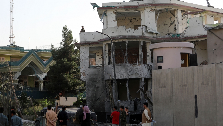Afghan security personnel inspect a damaged building in the aftermath of an attack in Kabul, Afghanistan People stand around a bombed-out building