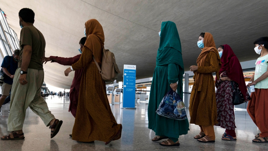 Families evacuated from Kabul, Afghanistan, walk through the terminal before boarding a bus after they arrived at Washington Dulles International Airport, in Chantilly, Virginia, on Friday, Aug. 27, 2021. Families evacuated from Kabul, Afghanistan, walk through the terminal before boarding a bus after they arrived at Washington Dulles International Airport, in Chantilly, Virginia, on Friday, Aug. 27, 2021.