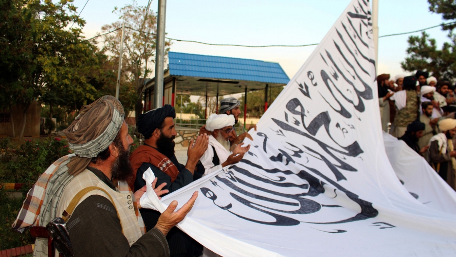 Taliban fighters pray while raising their flag at the Ghazni provincial governor's house, in Ghazni, southeastern, Afghanistan, Sunday, Aug. 15, 2021. Taliban fighters pray while raising their flag at the Ghazni provincial governor's house, in Ghazni, southeastern, Afghanistan, Sunday, Aug. 15, 2021.