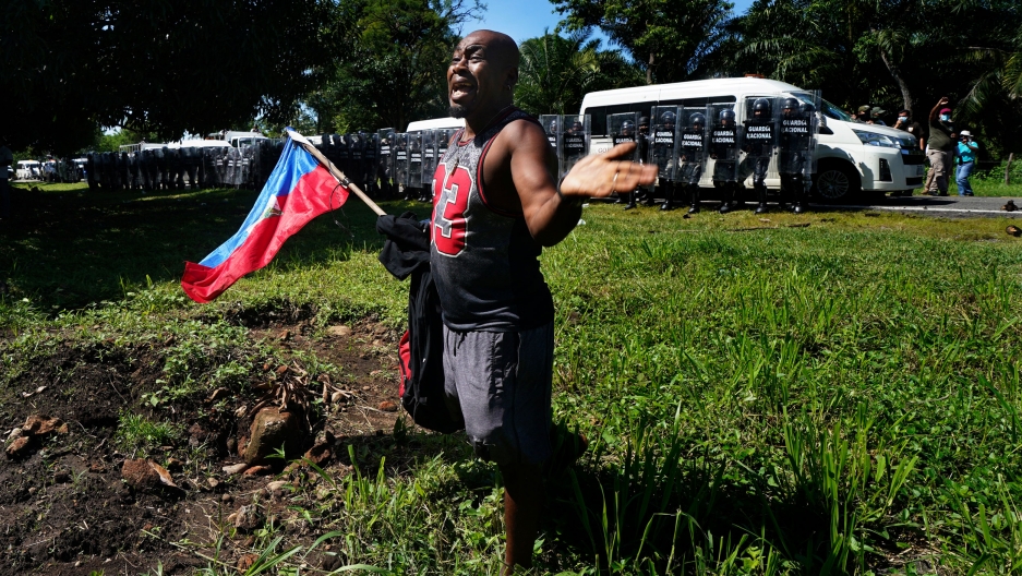 A Haitian migrant, holding his country's national flag, pleads with Mexican National guardsmen not to detain migrants making their way to the US-Mexico border, in Escuintla, Chiapas state, Mexico, Thursday, Sept. 2, 2021. A Haitian migrant, holding his country's national flag, pleads with Mexican National guardsmen not to detain migrants making their way to the US-Mexico border, in Escuintla, Chiapas state, Mexico, Thursday, Sept. 2, 2021.