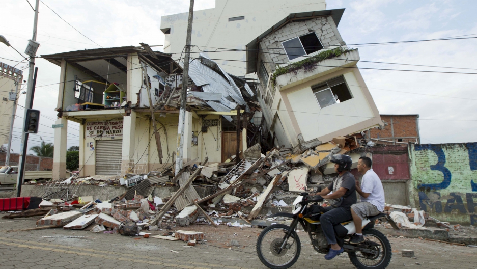 Men ride a motorcycle past damaged buildings in Pedernales after an earthquake struck off Ecuador's Pacific coast.