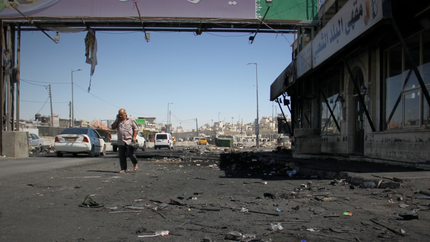 A man walks through the charred Qalandiya checkpoint after clashes between protesters and the Israeli army. A man walks through the charred Qalandiya checkpoint after clashes between protesters and the Israeli army.