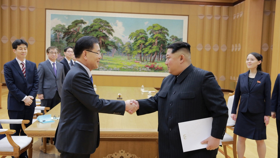 North Korean leader Kim Jong-un on the right shakes hands with a member of the special delegation of South Korea's President in a boardroom.