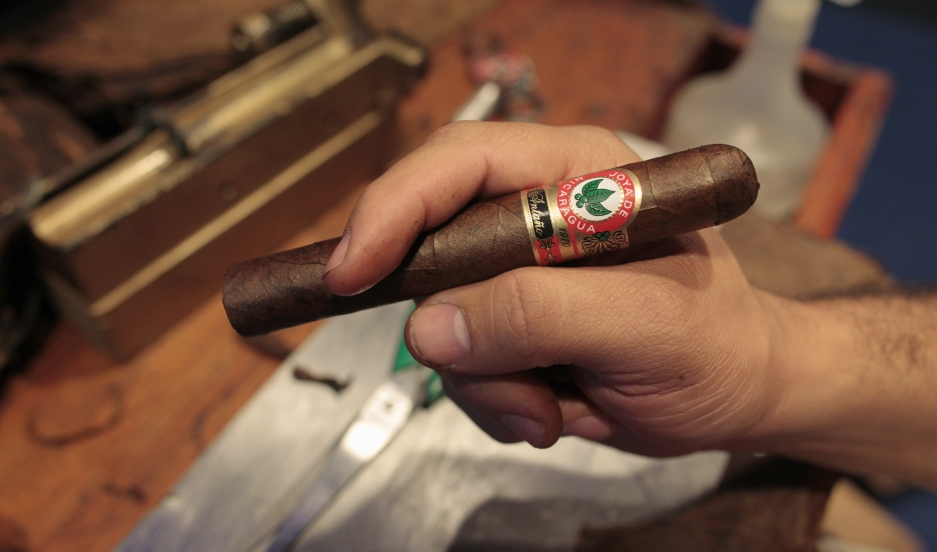 A man inspects a hand-rolled Hoyas de Nicaragua cigar during A man inspects a hand-rolled Hoyas de Nicaragua cigar during