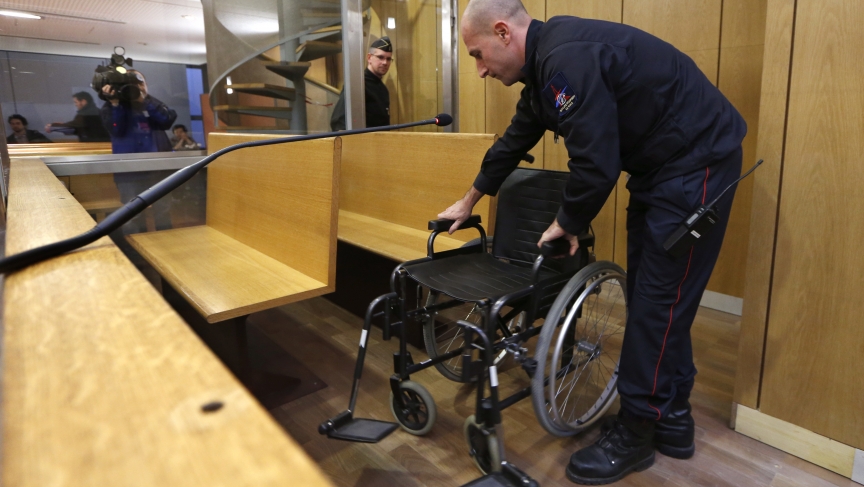 A fireman installs the wheelchair of former Rwandan army captain Pascal Simbikangwa before the start of his trial at a Paris court. 