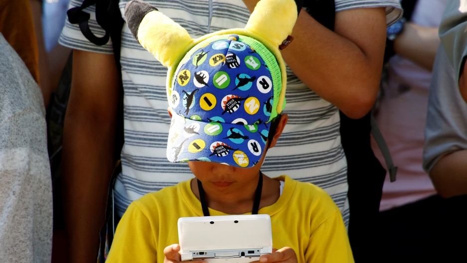 A boy in a Pikachu hat plays a Nintendo game console 