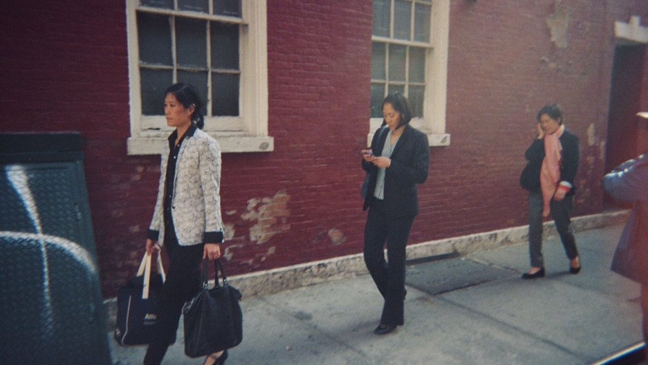 Three women walking on the sidewalk.