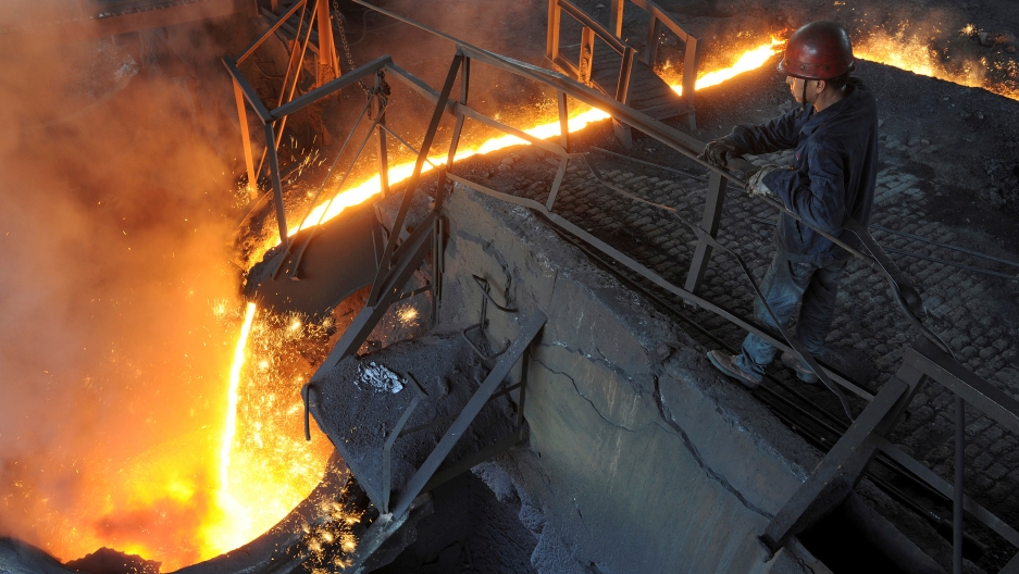 A worker monitors molten iron pouring into a furnace at steel manufacturing plant in Hefei, Anhui province, China. A worker monitors molten iron pouring into a furnace at steel manufacturing plant in Hefei, Anhui province, China.