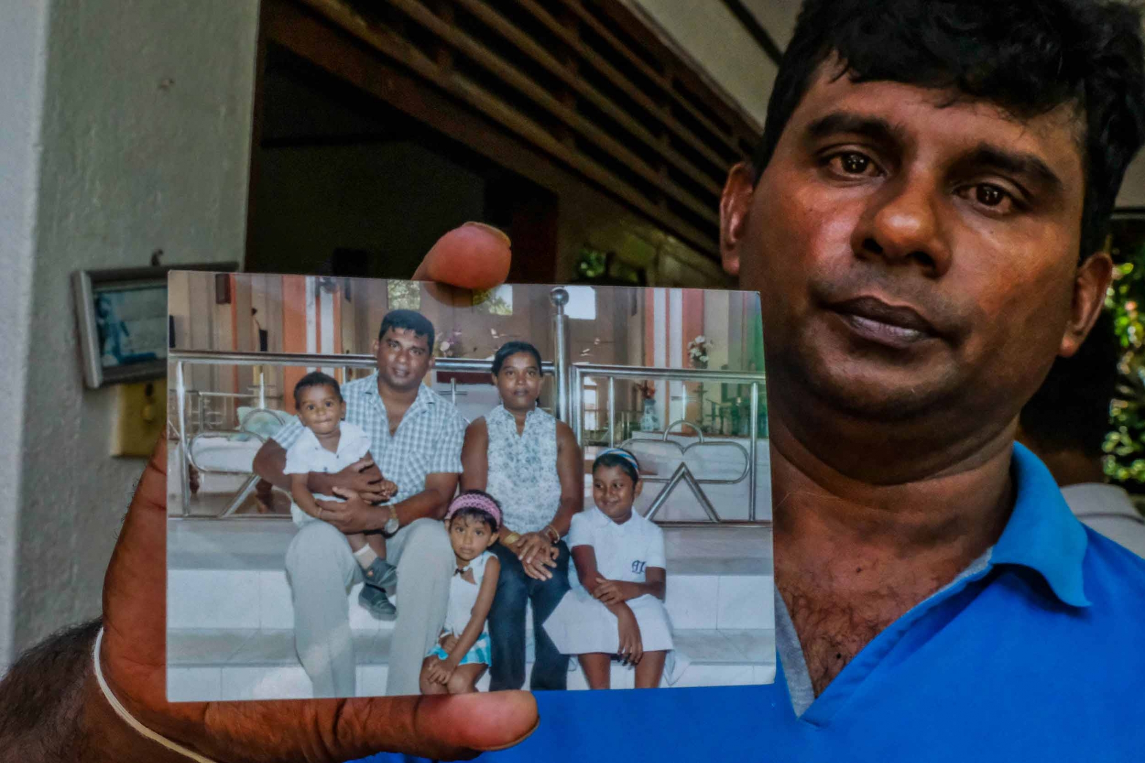 A man holds a photo of himself with his wife and three young children.