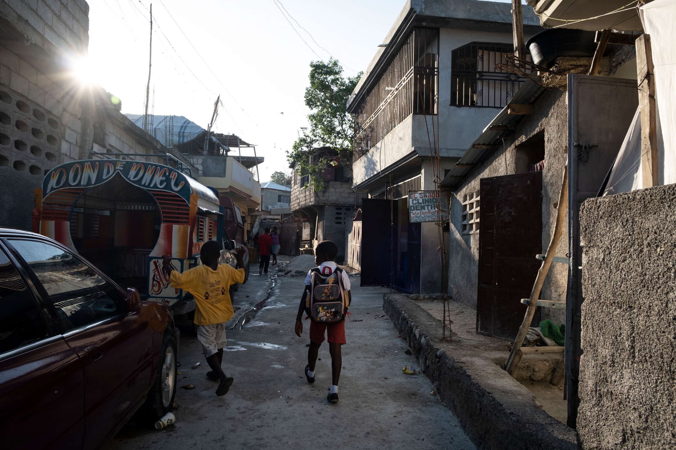 Children pass through Marie's neighborhood in Laboule, outside of Port-au-Prince, Haiti. Two children, one with a backpack, are shown walking through a neighborhood in Laboule, outside of Port-au-Prince, Haiti.
