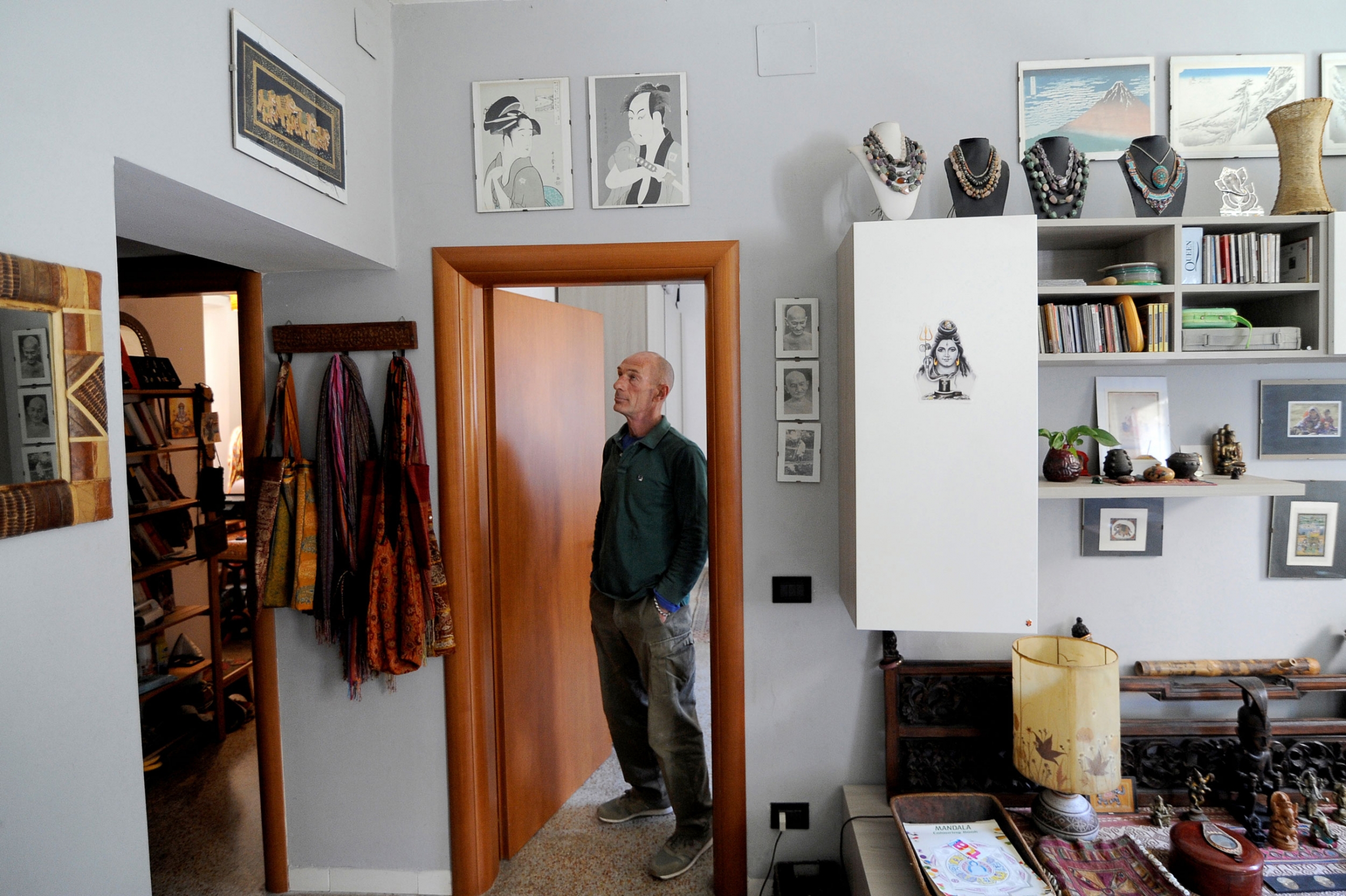 Carlo Spinazzi, 59, looks on in his illegally occupied apartment in Venice. A man is shown in a button down shirt standing in a brown wooden doorframe.