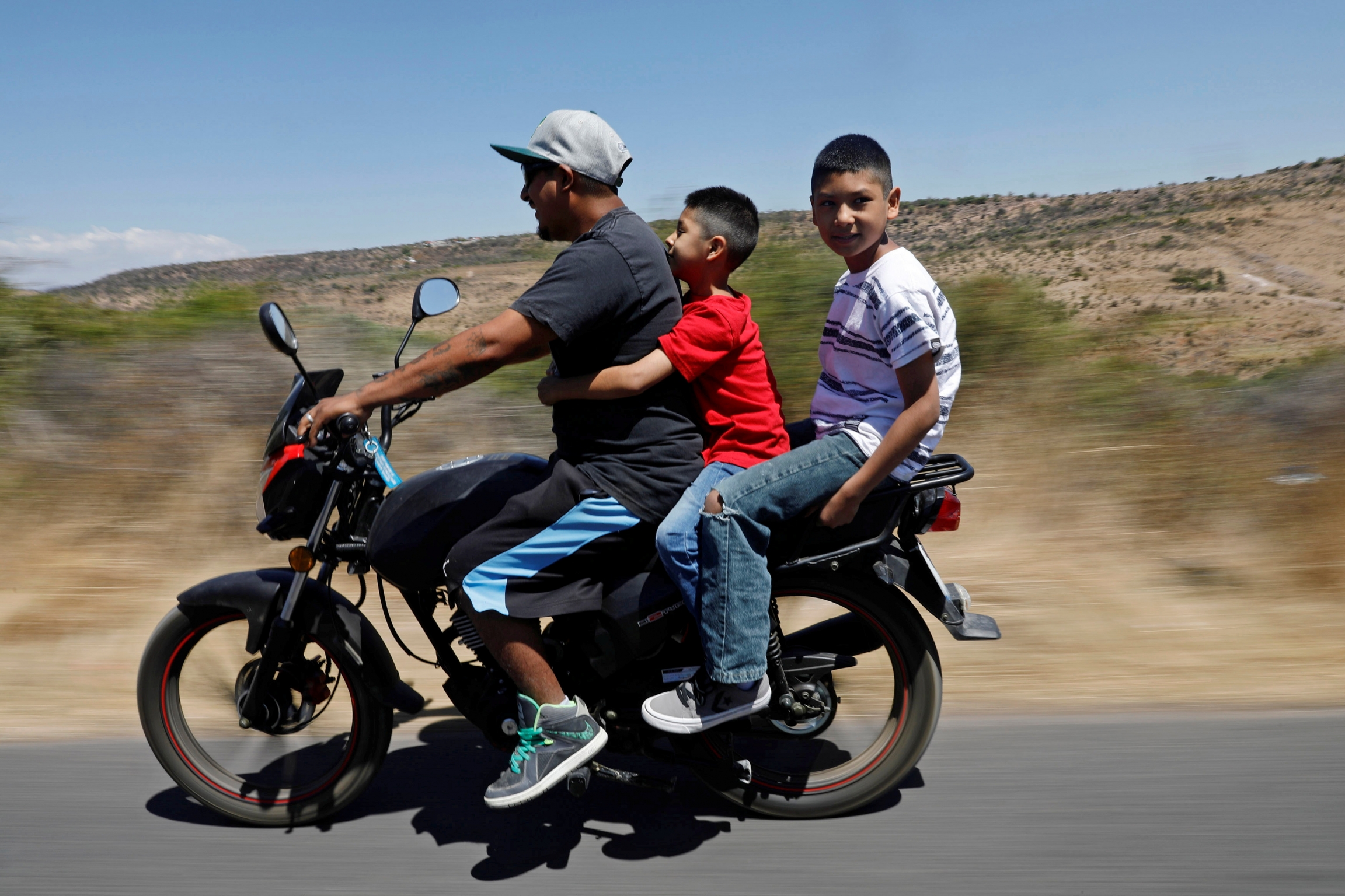 A man and two boys ride a motorcycle
