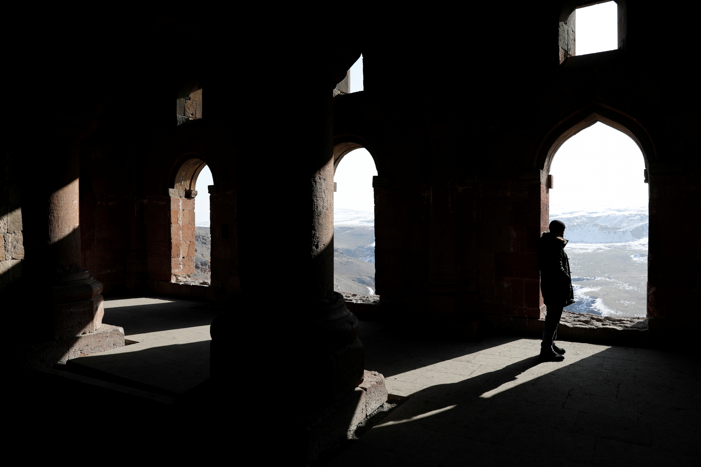 Un homme regarde le paysage sous les hautes arches d'un bâtiment ancien