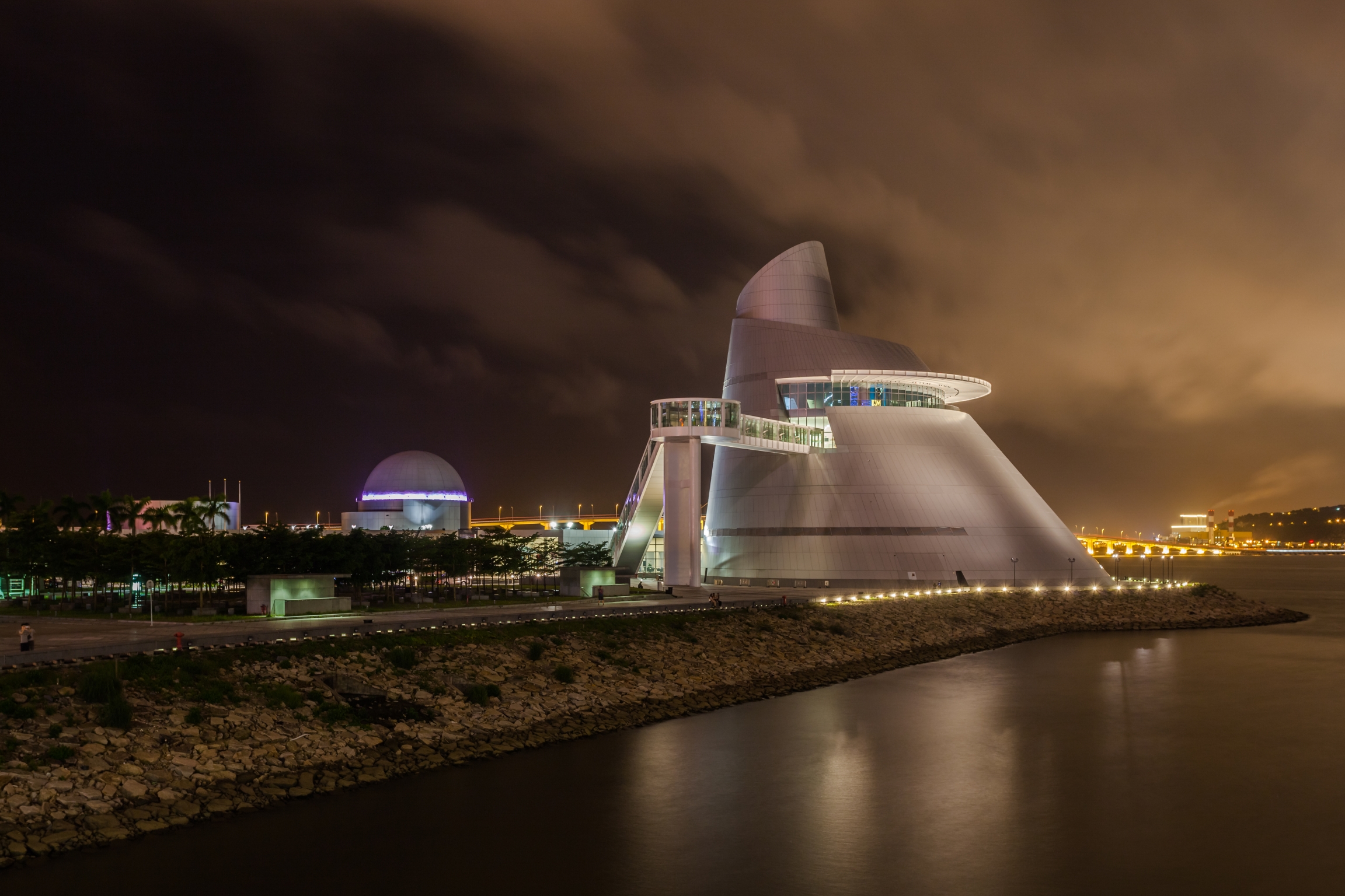 The Macau Science Center was completed in 2009 and has since become a major landmark of Macau. It features an exhibition center, planetarium, and convention center. A night time view of the Macau Science Center along the water.