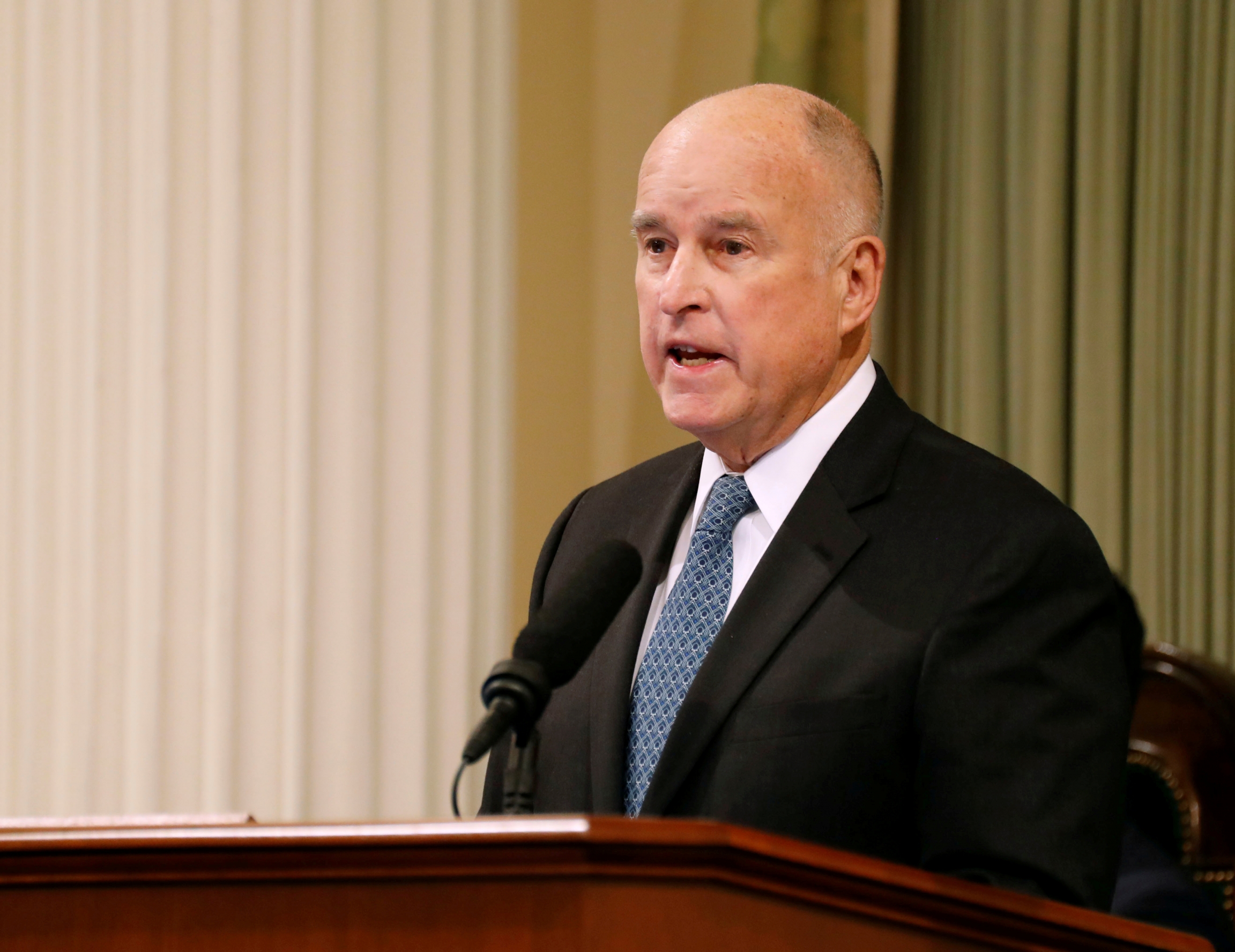Former California Governor Jerry Brown, who signed the Fair Day's Pay Act in 2015. Former Governor Jerry Brown stands at a podium.