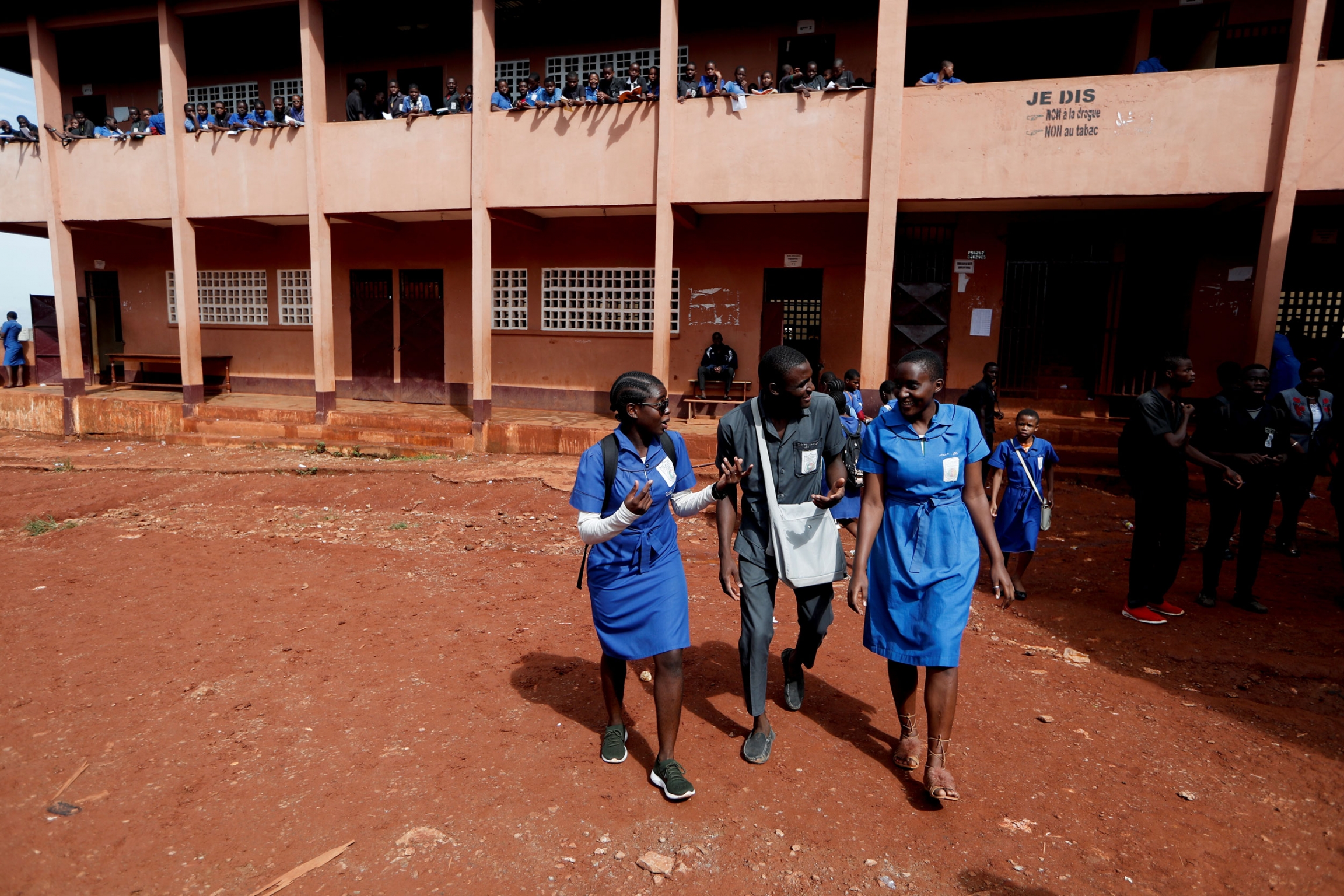 Asheri walks with her classmates. Two young women are shown walking on either side of a young man talking.